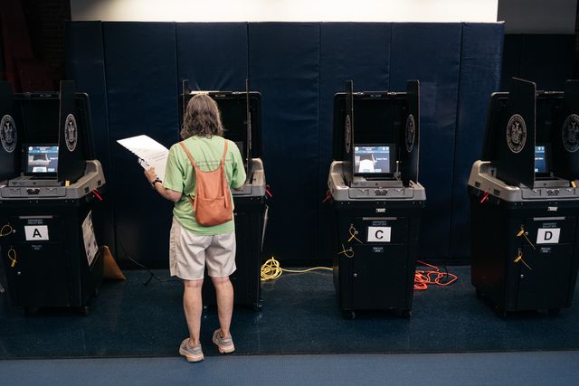 A voter pushes her ballot through a vote scanner at the Park Slope Armory during the August 23 primary.